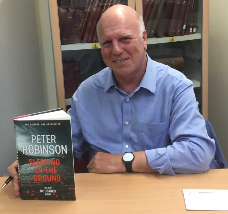 Image: Photograph of Peter Robinson presenting his book Sleeping in the Ground